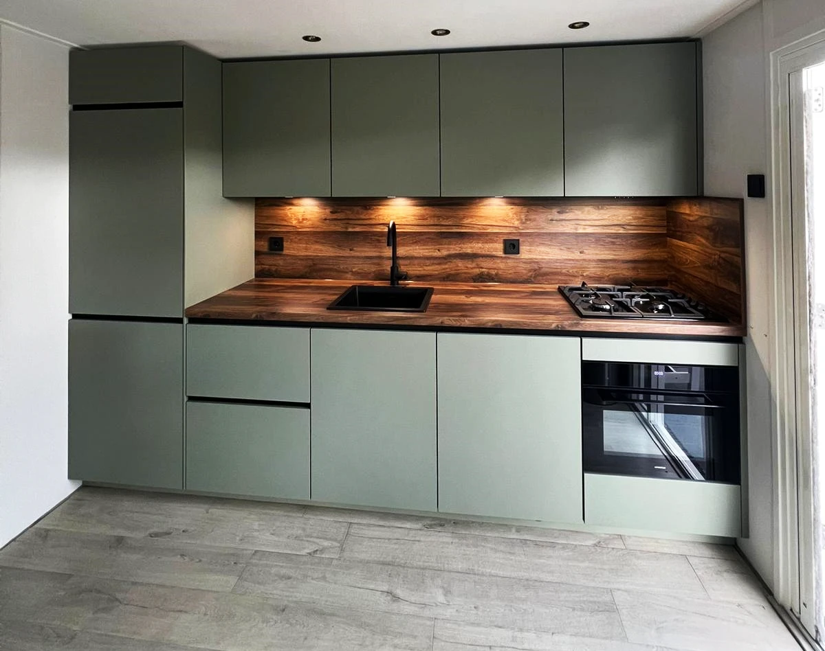 Groene keuken met een houtlook werkblad en achterwand Groene keuken met een houtlook werkblad en achterwand